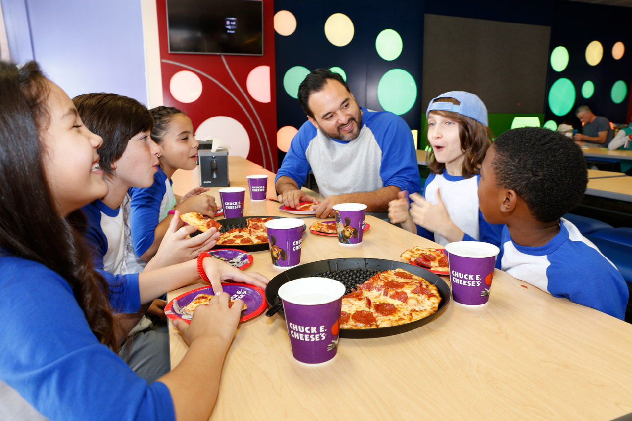 Kids team at table eating pizza