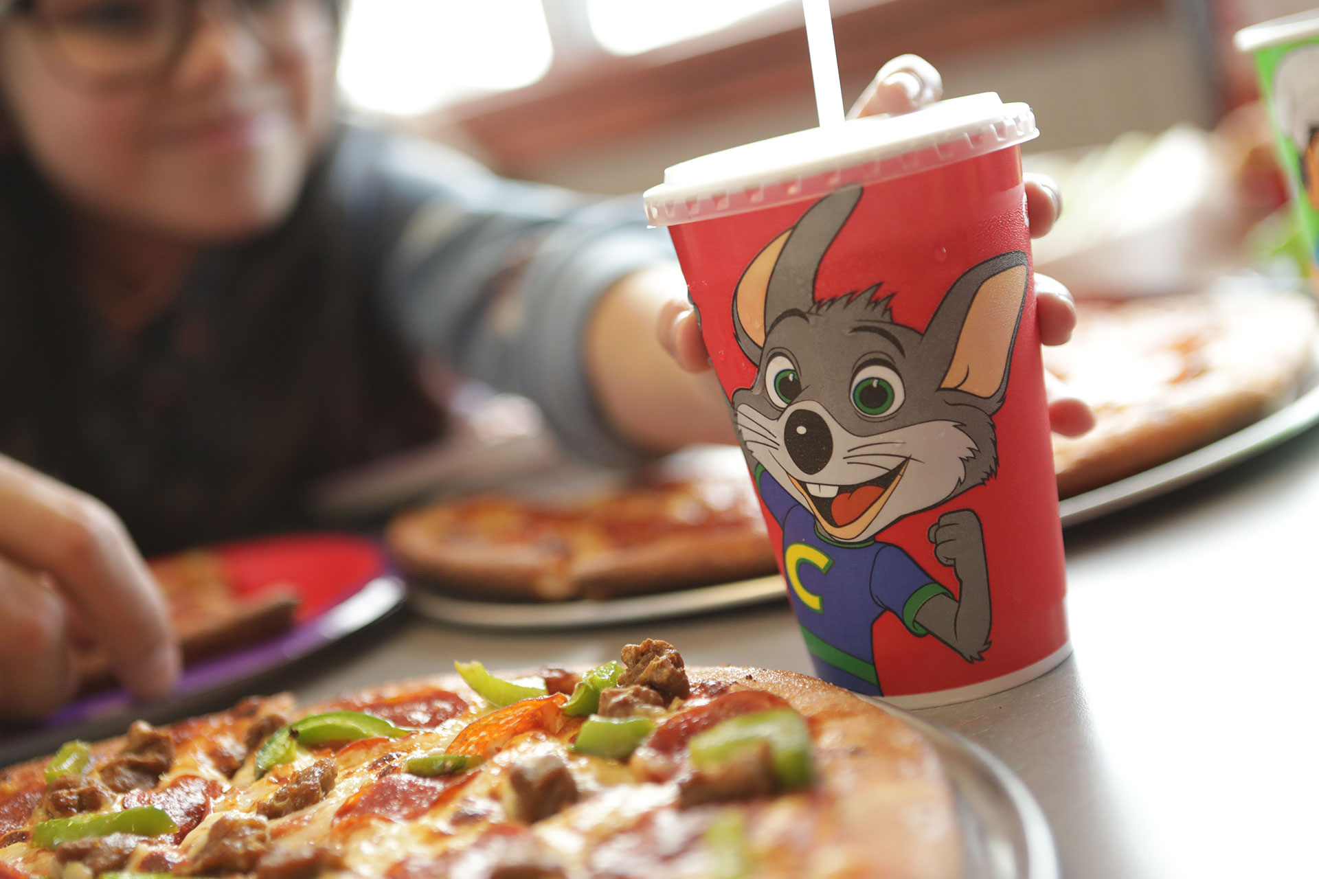 Hand reaching for Chuck E. Cheese up by pizza